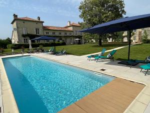 a swimming pool with blue chairs and an umbrella at Hermitage, Gites Villeblanche in La Chapelle-Pouilloux