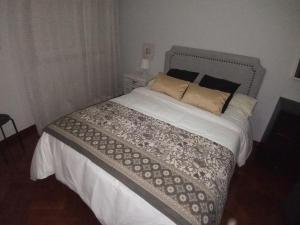 een slaapkamer met een groot bed met witte lakens en kussens bij Espiguiñas in Muros +2 foto's