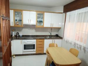 een keuken met witte kasten, een tafel en een wastafel bij Espiguiñas in Muros