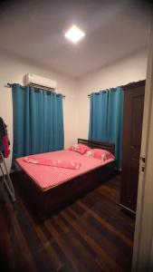 a bedroom with blue curtains and a bed with red sheets at Cozy two bedroom Apartment GiJa in Paramaribo
