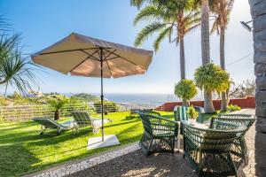 eine Terrasse mit Tisch und Stühlen und einem Sonnenschirm in der Unterkunft BioFuncho Garden Residence in Funchal
