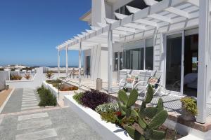 a white house with chairs and plants on the porch at 19 ocean villas in Yzerfontein