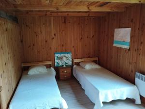 two beds in a room with wooden walls at grange aménagée in Mimizan