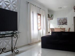 a living room with a black couch and a flat screen tv at Quarto 5 próximo ao aeroporto internacional in Belém