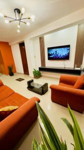 a living room with orange furniture and a flat screen tv at Castellares la Puebla Hostelería Departamento in Ayacucho