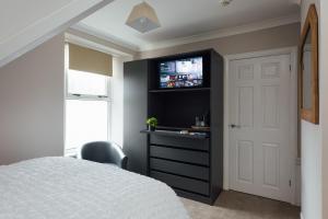 a bedroom with a bed and a tv on a wall at The Dolphin Hotel & Restaurant in Pembroke Dock