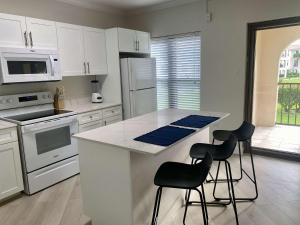 a kitchen with white cabinets and a counter with stools at Oceanfront Condo on Seven Mile Beach in Dog City