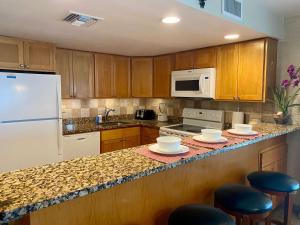 a kitchen with wooden cabinets and a white refrigerator at Oceanfront 3-BR Condo with Large Beachfront Terrace in Dog City
