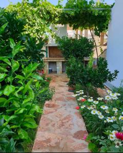 a garden with flowers and a stone pathway at Guesthouse Mance in Ksamil