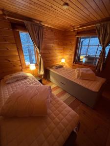 a bedroom with two beds in a log cabin at Forest and Lake Chalet in Pallas-Yllastunturi, Levi in Kittilä