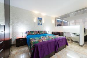 a bedroom with a bed with a purple blanket at Suites Garden Loft Dalí in Las Palmas de Gran Canaria