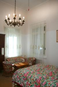 バーリにあるB&B Villa Pallanteのベッドルーム1室(ベッド1台、椅子、シャンデリア付)