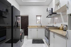 a white kitchen with a sink and a stove at Shortlet spaces in Lagos