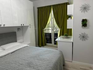 a bedroom with a bed and a window with green curtains at Verdana apartament in Timişoara