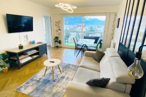 een woonkamer met een bank en een tafel bij Panorama Stay, Pool, Balcony and Mountain View in Annecy