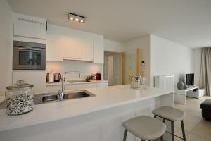 a white kitchen with a sink and a counter at Residentie Rivella in Koksijde