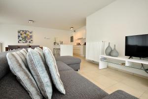 un soggiorno con un divano e una televisione di Residentie Rivella a Koksijde