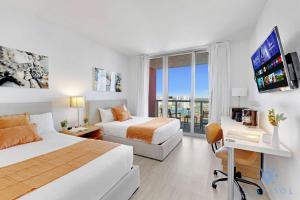 a hotel room with two beds and a flat screen tv at Amazing Balcony Near Beach in Hallandale Beach