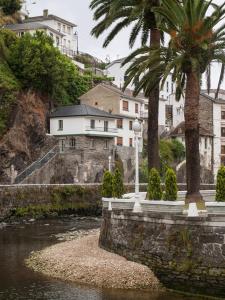 a river with palm trees and buildings in the background at La Casa De Luarca in Luarca