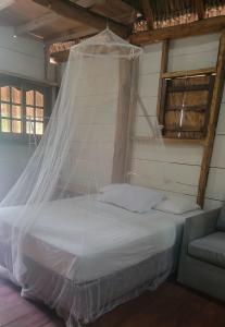 a bed with a mosquito net in a room at Coconut Surf in El Gigante