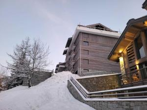 a building in the snow next to a building at Charmant T4 rénové proche pistes, parking, Wifi - FR-1-575-33 in Courchevel