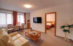 uma sala de estar com um sofá e um quarto com uma cama em Golf&Wellness Resort Alfrédov em Alfrédov