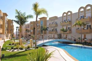 a bridge over a swimming pool in front of a building at Résidence les dunes in Hammam Sousse