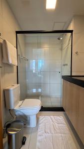 a bathroom with a toilet and a glass shower at Studio Confortável em Muro Alto in Ipojuca +11 photos