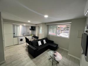 a living room with a black couch and a kitchen at El Encanto Andaluz 1 in Córdoba