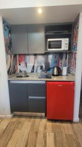 a kitchen with a microwave and a red refrigerator at MONOAMBIENTE VILAUT Temporario in Córdoba