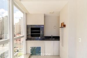 une cuisine avec des placards blancs et une grande fenêtre dans l'établissement 3Q Varanda c/ churrasqueira a 250m do mar! GGR0702, à Itapema