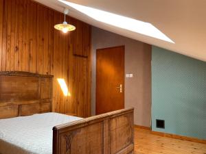 a bedroom with a bed and a wooden wall at Maison de charme en pierres, proche de la nature, idéale pour balades, proche Épinal - FR-1-589-73 in Girancourt