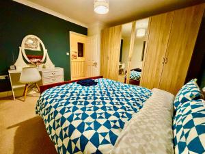 a bedroom with a blue and white bed and a mirror at Conveniently located 3 bed spacious home for couples, families and groups in Ipswich in Ipswich