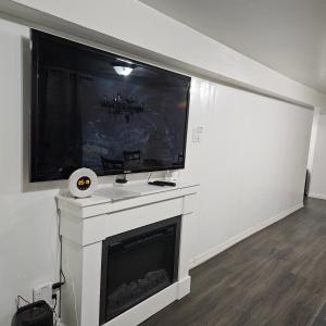 a living room with a large flat screen tv above a fireplace at Queen bedroom in Toronto