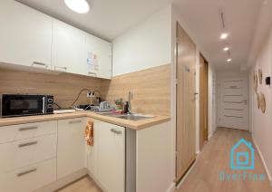 グダニスクにあるCoral Room - 1 km to Baltic Sea & 15 Minutes to Gdańsk Old Townのシンクと電子レンジを備えた白いキッチン