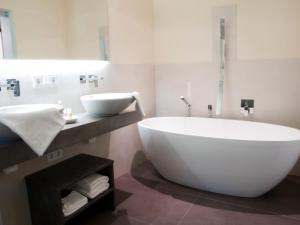 een witte badkamer met een groot bad en een wastafel bij Alpresort Tirol in Reith bei Seefeld