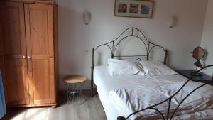 a bedroom with a bed and a wooden cabinet at Charmante maison de pays dans le centre de St Denis D'Oléron in Saint-Denis-dʼOléron