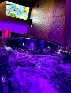 Una bañera morada con un televisor en una habitación. en Love Room Spa - Sauna - Hammam, en Domérat
