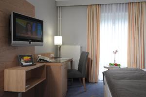 um quarto de hotel com uma cama e uma televisão na parede em Best Western Hotel Der Föhrenhof em Hanôver