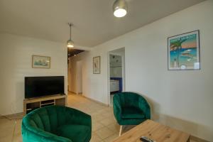 salon z 2 zielonymi krzesłami i telewizorem w obiekcie Mqsl25 w mieście Sainte-Luce