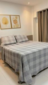 a bedroom with a bed with a checkered blanket at Makia Beach experience Flat 115 A in Porto De Galinhas +7 photos