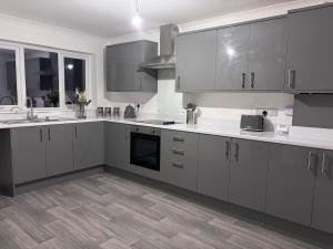 a kitchen with white cabinets and a wooden floor at Modern 3 bedroom detached house in Sutton Bridge +14 photos
