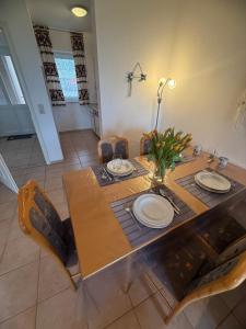 a dining room table with plates and flowers on it at Bei den Leuchttürmen in Fehmarn +27 photos