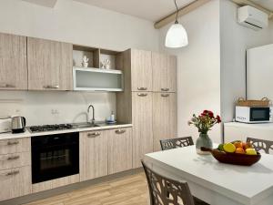 - une cuisine avec des placards en bois et une table avec un bol de fruits dans l'établissement La Residenza, appartamento centrale e moderno - Marea Stays Collection, à Nardò 25 autres photos
