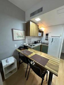 圣保罗Flat Aconchegante nos Jardins的厨房配有桌子、椅子和冰箱。