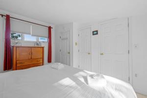 ein weißes Schlafzimmer mit einem Bett und einem Fenster in der Unterkunft Lake Home with Private Beach and Hot Tub in Ossipee