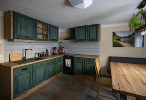 a kitchen with green cabinets and a wooden table at Heimathaus Hettegger in Grossarl