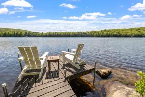 two chairs sitting on a dock on a lake at Pond Retreat at the Beach in New Durham