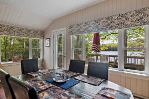 ein Esszimmer mit Tisch und Stühlen und Fenstern in der Unterkunft Pond Retreat at the Beach in New Durham