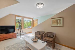 ein Wohnzimmer mit einem TV, Stühlen und einem Tisch in der Unterkunft Pond Retreat at the Beach in New Durham